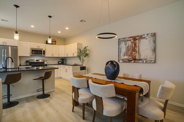 kitchen with stainless steel appliances, visible vents, light wood-type flooring, tasteful backsplash, and dark countertops