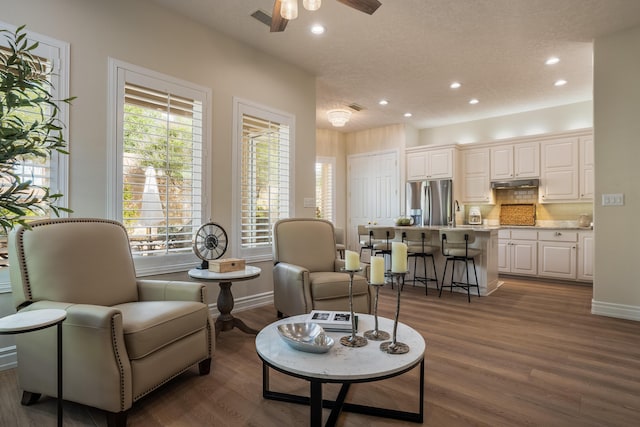 living area with recessed lighting, wood finished floors, visible vents, and baseboards