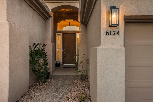 entrance to property featuring a garage and stucco siding