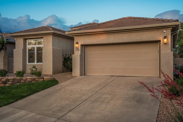 view of front of house with stucco siding, a garage, concrete driveway, and a tiled roof