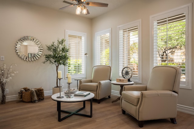 living area with wood finished floors, baseboards, and ceiling fan