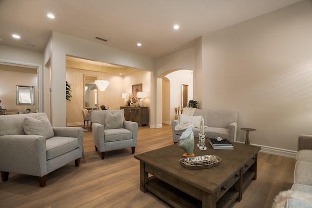 living area featuring wood finished floors, visible vents, baseboards, recessed lighting, and arched walkways