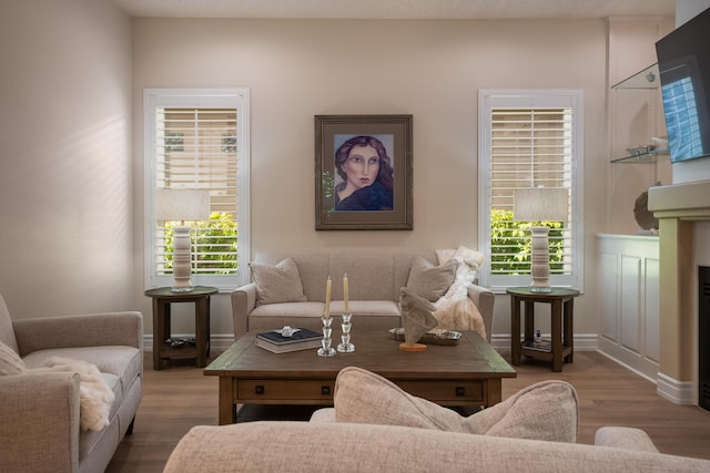 living area with a fireplace, baseboards, and wood finished floors