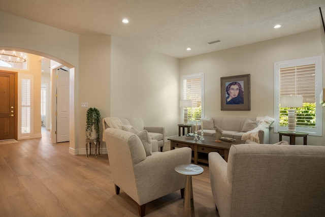 living room featuring recessed lighting, light wood-style floors, arched walkways, and baseboards