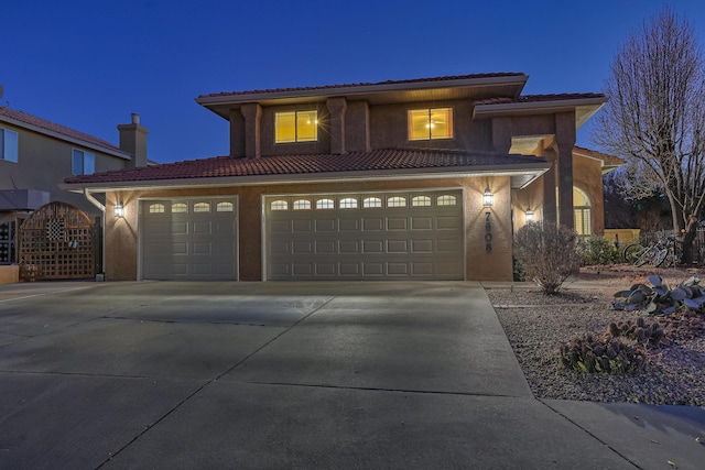 view of front of house with driveway, a tiled roof, an attached garage, and stucco siding