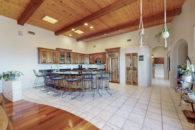 kitchen with a kitchen bar, stainless steel microwave, dark countertops, a peninsula, and brown cabinetry