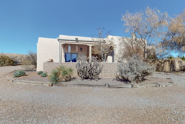 adobe home featuring a fenced front yard and stucco siding