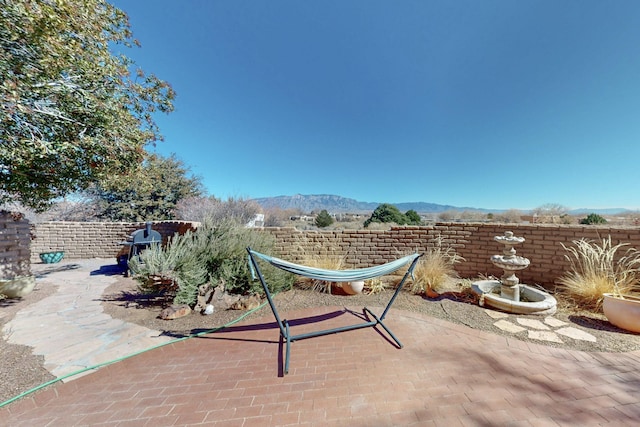 view of patio featuring fence and a mountain view