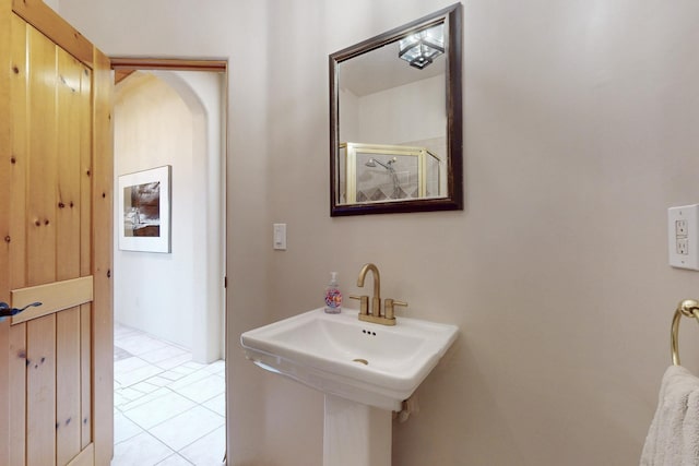 bathroom with tile patterned flooring, a shower with door, and a sink