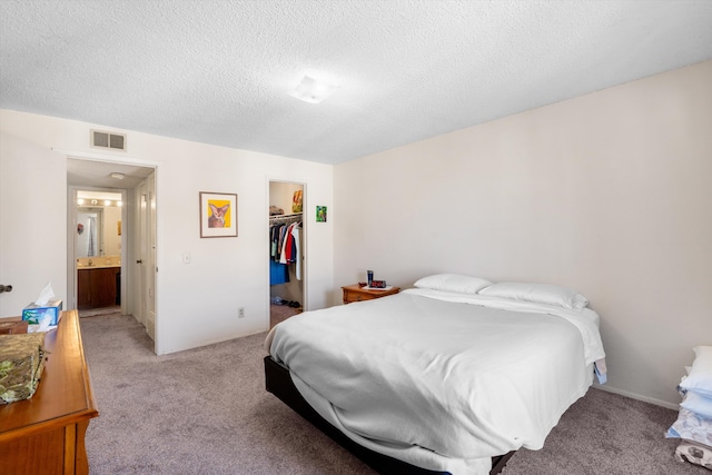 bedroom featuring light carpet, a spacious closet, a textured ceiling, and visible vents