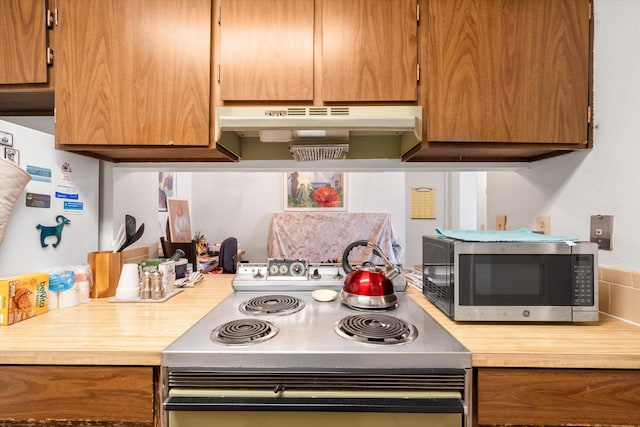 kitchen featuring under cabinet range hood, electric range, light countertops, brown cabinets, and stainless steel microwave