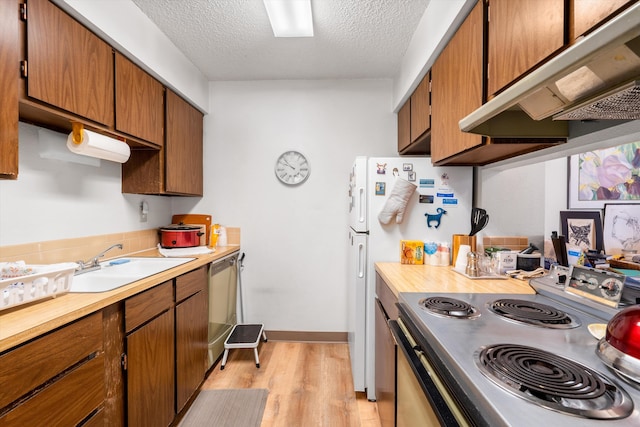 kitchen with appliances with stainless steel finishes, light countertops, a sink, and under cabinet range hood