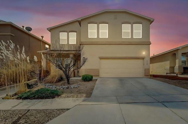 view of front facade with concrete driveway, an attached garage, and stucco siding