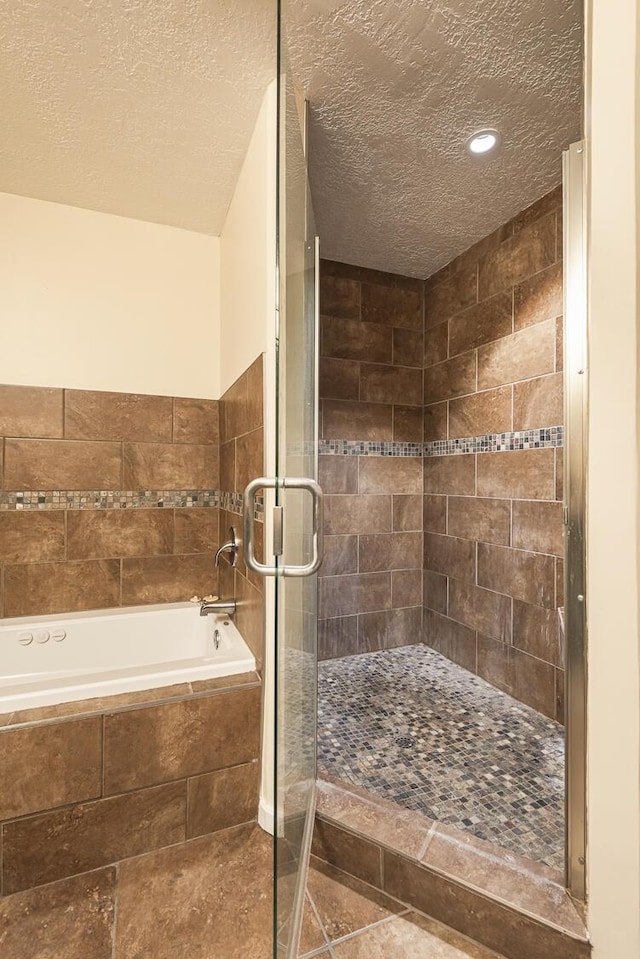 full bath featuring a shower stall, a textured ceiling, and a bath