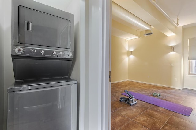 laundry area with tile patterned flooring, laundry area, stacked washer / dryer, visible vents, and baseboards