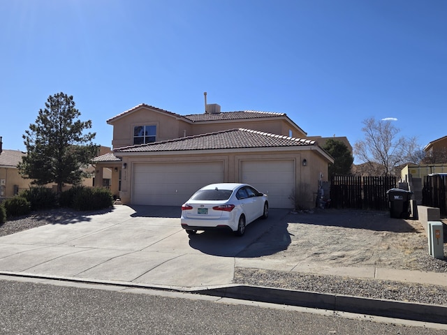 view of front of home featuring an attached garage, fence, a tile roof, concrete driveway, and stucco siding