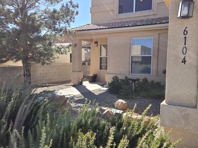 exterior space with a tiled roof, fence, and stucco siding