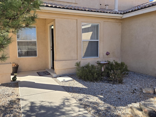 view of exterior entry featuring a tile roof and stucco siding