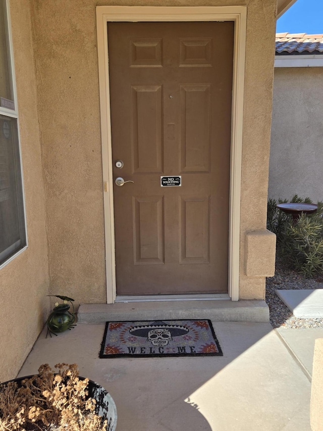 property entrance featuring a tile roof and stucco siding