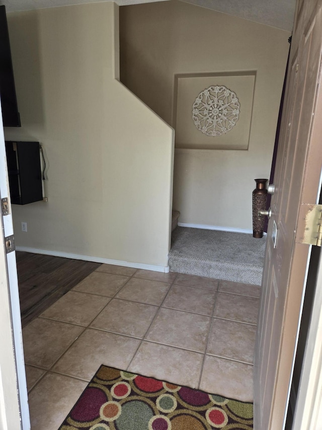 interior space with vaulted ceiling, baseboards, and tile patterned floors