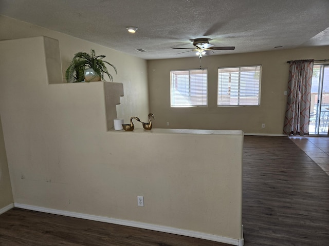 spare room featuring baseboards, dark wood finished floors, and a textured ceiling