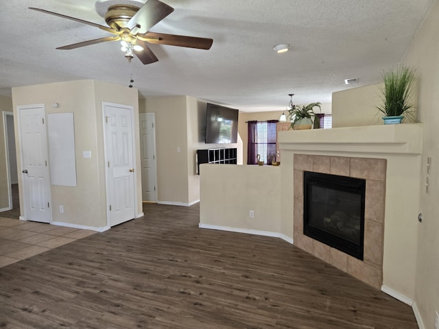 unfurnished living room featuring a textured ceiling, wood finished floors, and a tiled fireplace