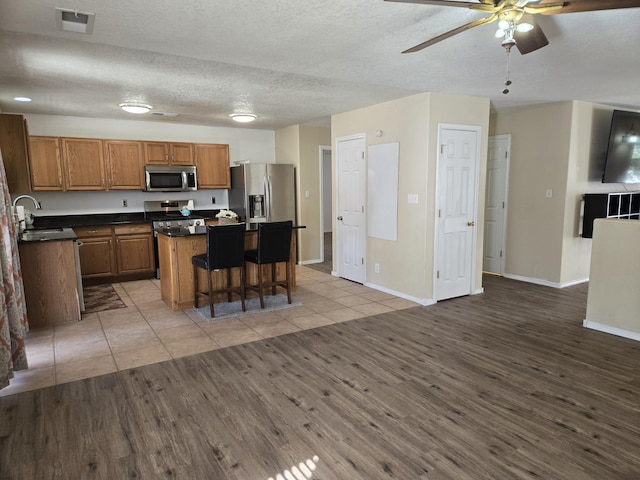 kitchen with visible vents, open floor plan, a center island, stainless steel appliances, and a sink