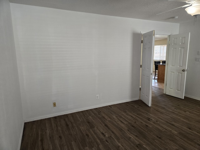 empty room featuring dark wood-style floors, a textured ceiling, baseboards, and a ceiling fan