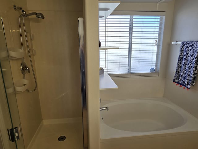 bathroom featuring a stall shower, a garden tub, and a healthy amount of sunlight