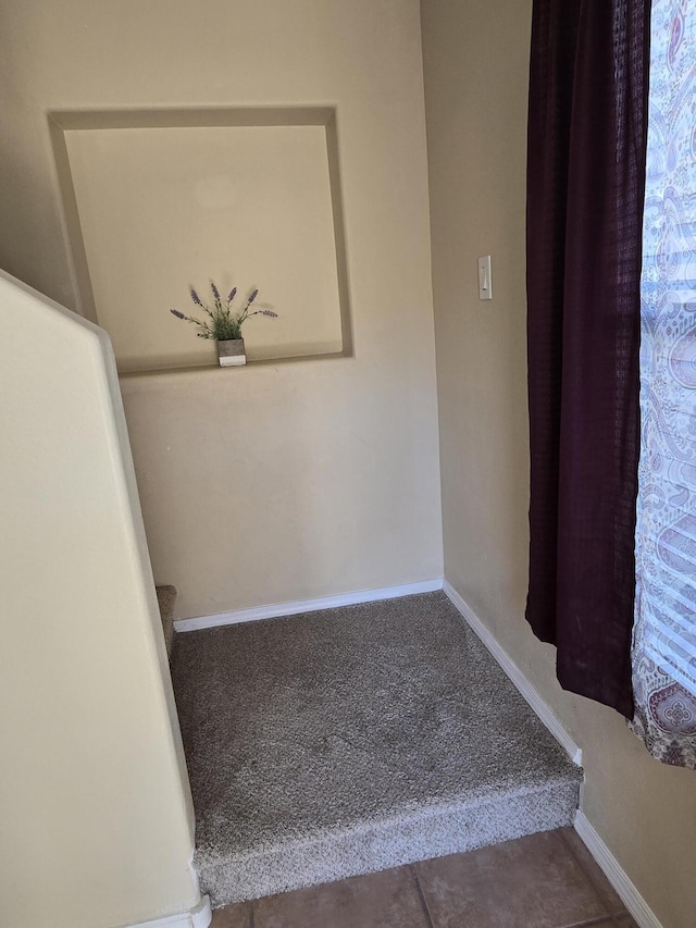 staircase featuring baseboards and carpet flooring