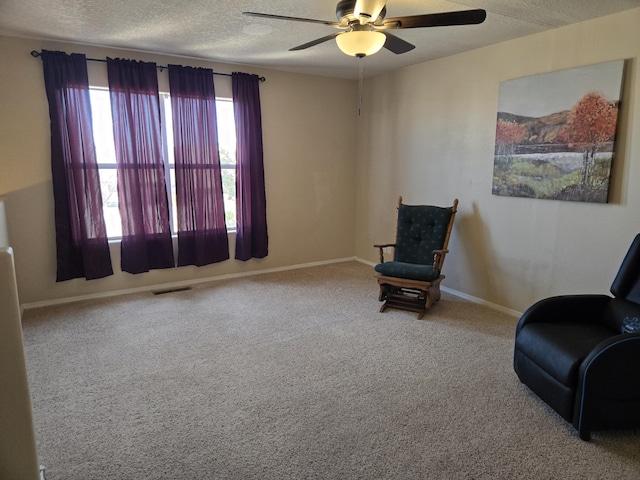 living area with baseboards, visible vents, ceiling fan, a textured ceiling, and carpet floors