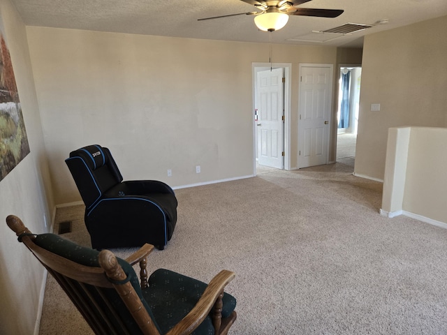 living area featuring light carpet, a textured ceiling, visible vents, and baseboards