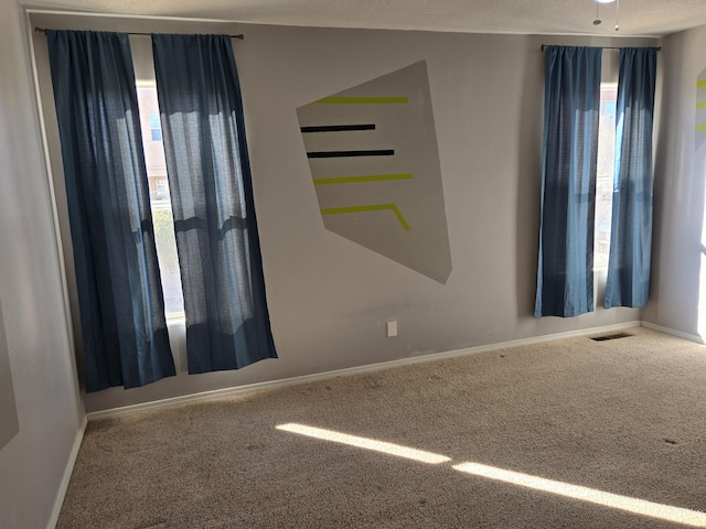 carpeted spare room featuring visible vents and baseboards