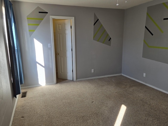 empty room with carpet flooring, visible vents, and baseboards