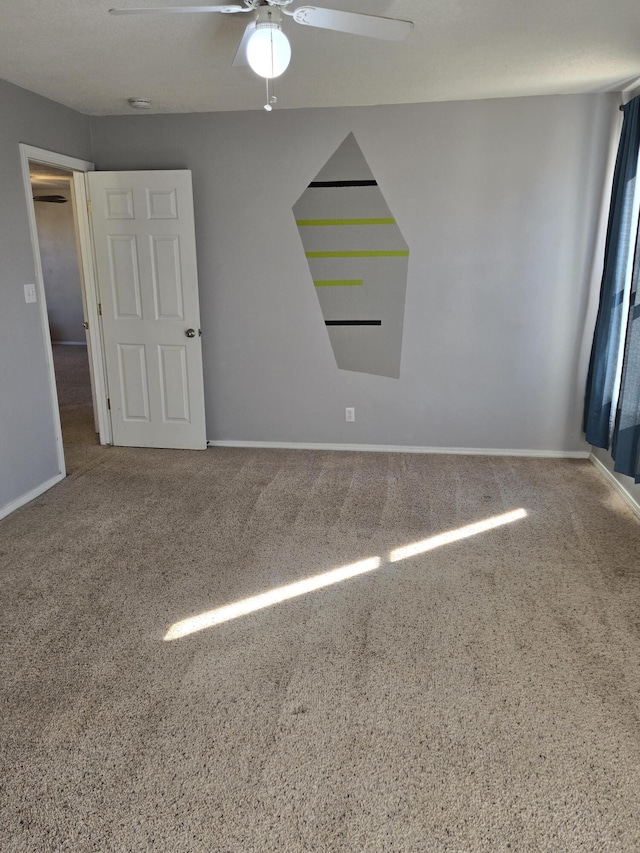 unfurnished room with carpet, baseboards, and ceiling fan