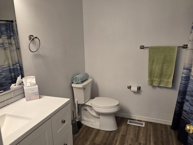 full bath featuring toilet, wood finished floors, vanity, visible vents, and baseboards