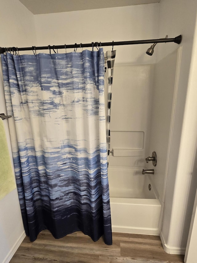 bathroom featuring shower / tub combo, wood finished floors, and baseboards