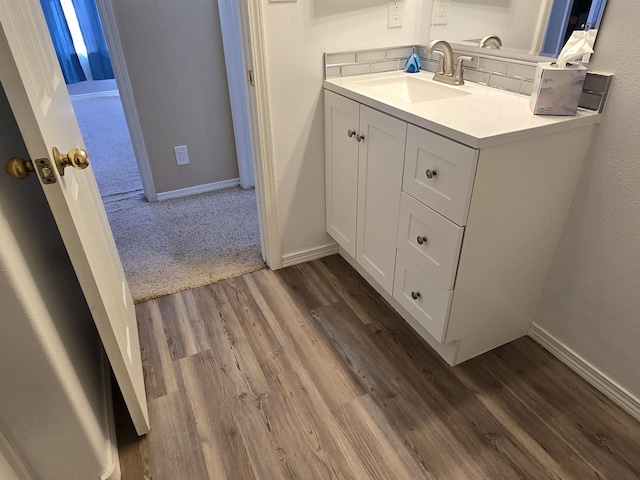 bathroom featuring baseboards, wood finished floors, and vanity