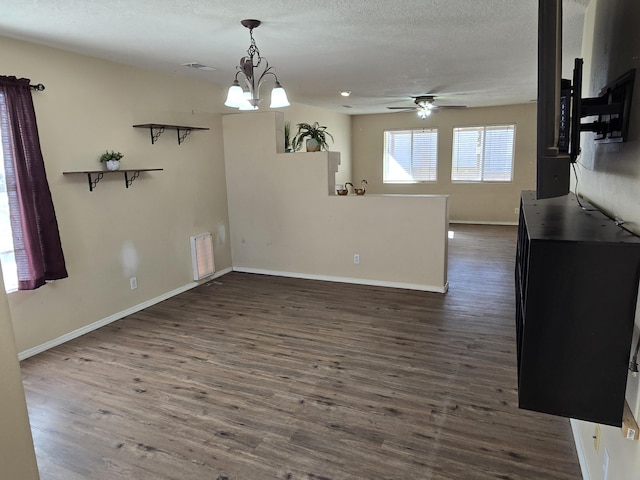 interior space featuring a textured ceiling, ceiling fan with notable chandelier, wood finished floors, visible vents, and baseboards