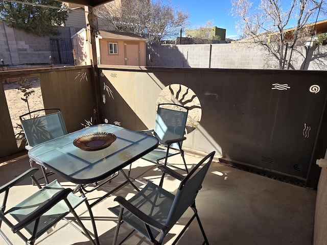 view of patio / terrace featuring a storage shed, outdoor dining space, an outdoor structure, and a fenced backyard