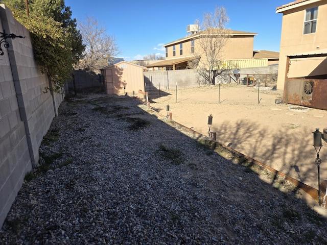 view of yard featuring a storage shed, a fenced backyard, and an outdoor structure