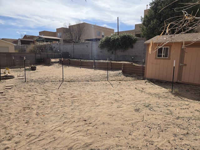 view of yard with a garden, a fenced backyard, an outdoor structure, and a storage unit