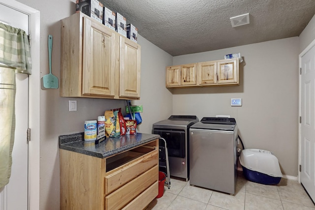 clothes washing area with cabinet space, light tile patterned floors, visible vents, washer and clothes dryer, and a textured ceiling