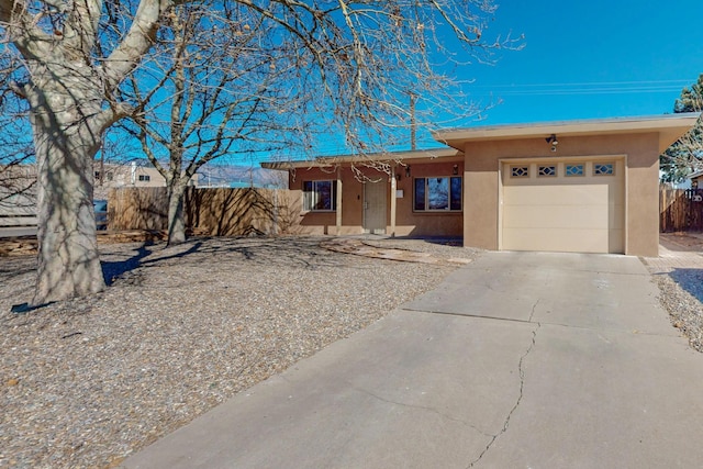 view of front facade featuring a garage, driveway, fence, and stucco siding