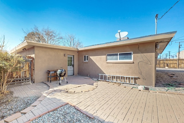 rear view of house featuring fence, a patio, and stucco siding