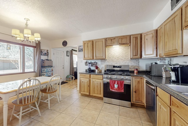 kitchen with decorative light fixtures, a notable chandelier, light tile patterned floors, stainless steel appliances, and dark countertops