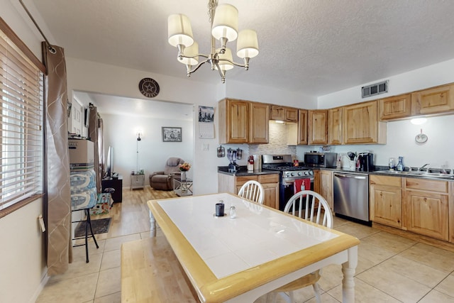 kitchen featuring light tile patterned floors, stainless steel appliances, visible vents, a sink, and a textured ceiling