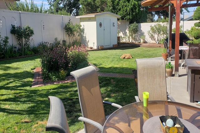 view of yard with an outbuilding, outdoor dining area, a fenced backyard, and a storage shed