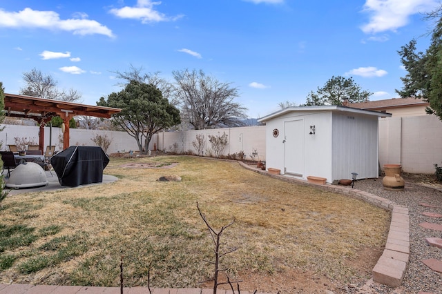 view of yard with a fenced backyard, a storage unit, and an outbuilding