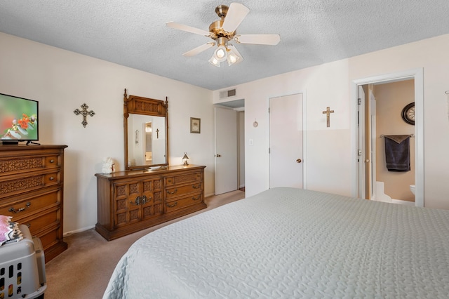 bedroom featuring visible vents, light colored carpet, ceiling fan, ensuite bathroom, and a textured ceiling